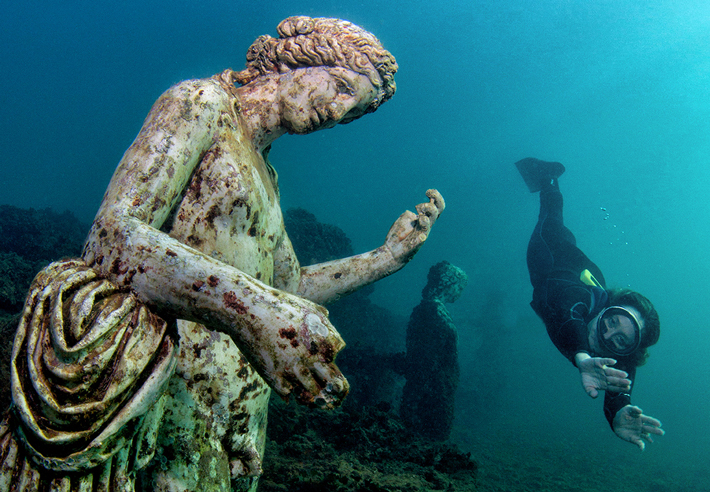 A diver swims by a replica of a statue of Dionysus, the god of wine, in the nymphaeum at Baiae. (Paquale Vassallo)