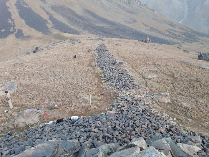 Rock walls near the Almosi Gorge inscription formed a rectangular enclosure measuring about 400 by 165 feet. Bobomulloev believes it may have once been used by Kushan nobility as a hunting enclosure.